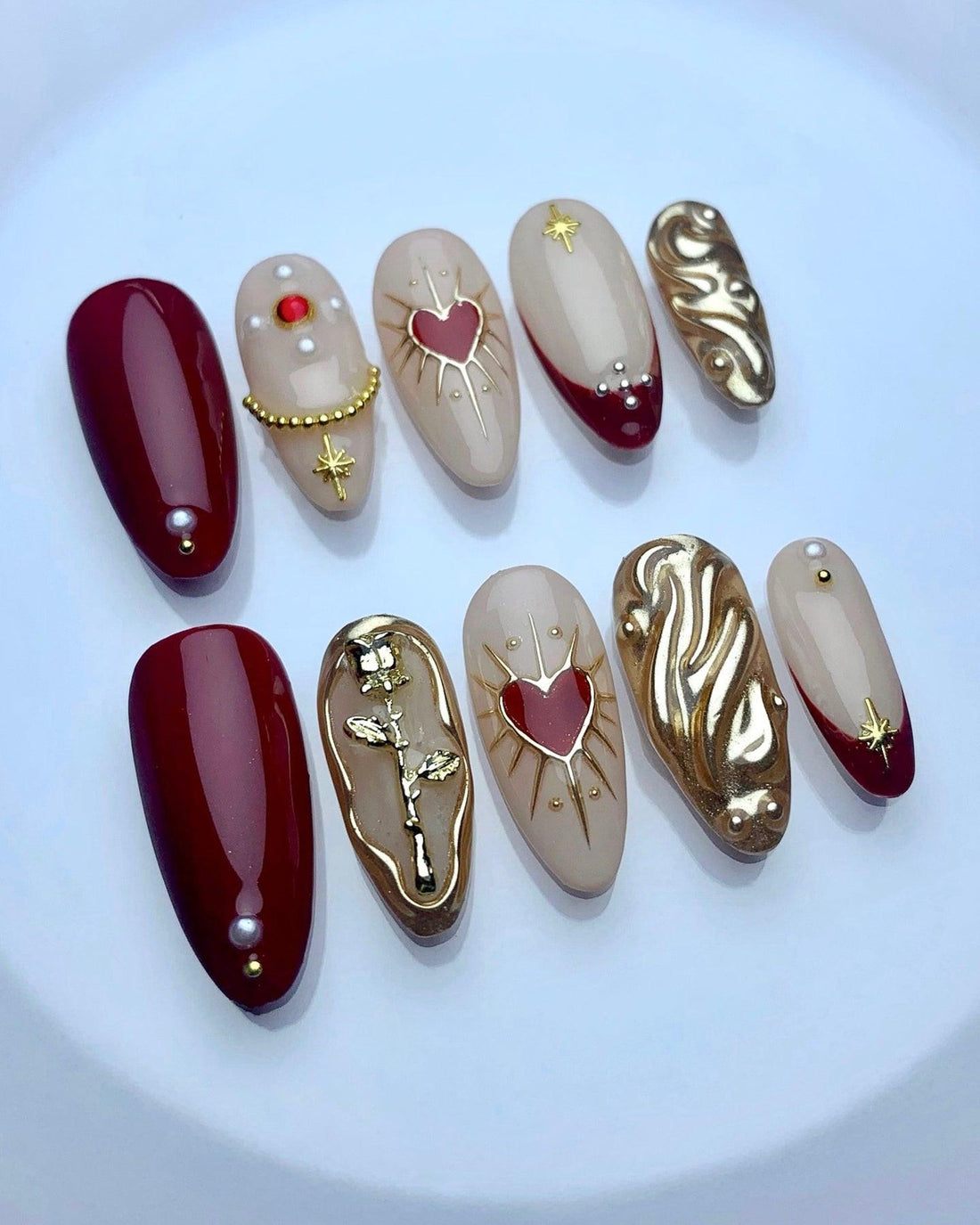 Handmade press-on nails with red, gold, and nude designs, heart and rose accents, reusable