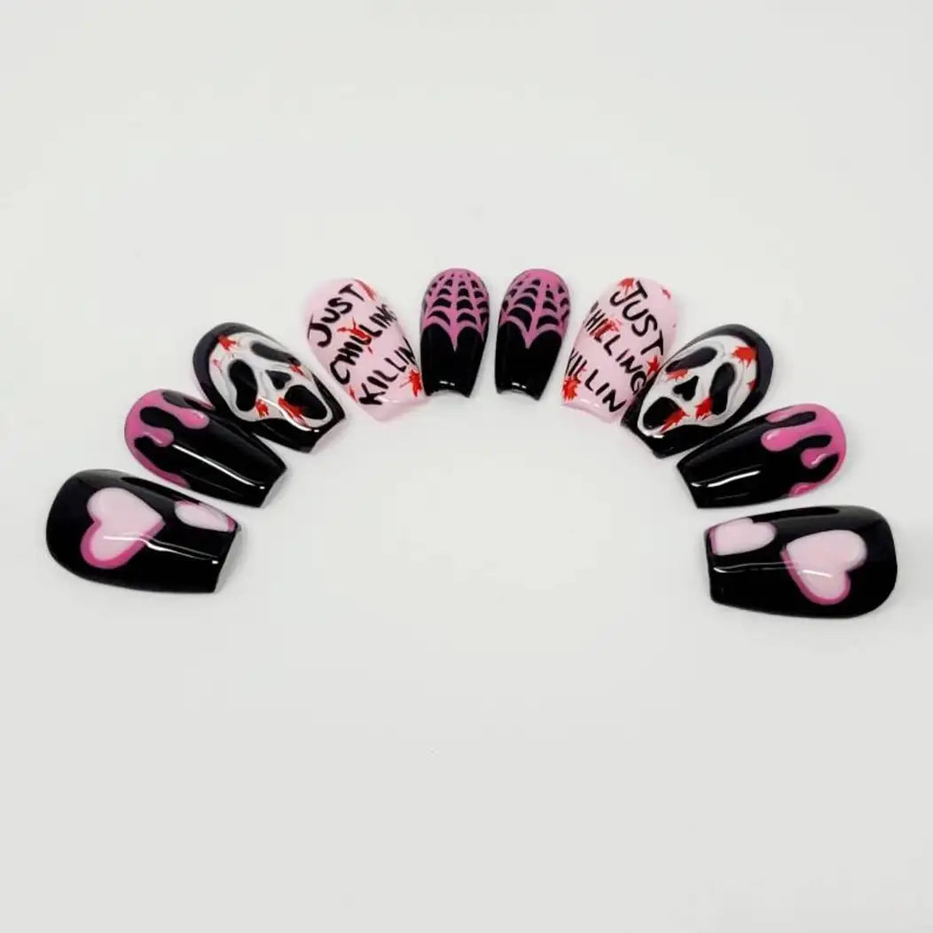 Handmade press-on nails with pink hearts, flames, spider webs, skull faces, and text design