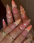 Long handmade press-on nails with 3D floral and geometric designs in peach and pink hues