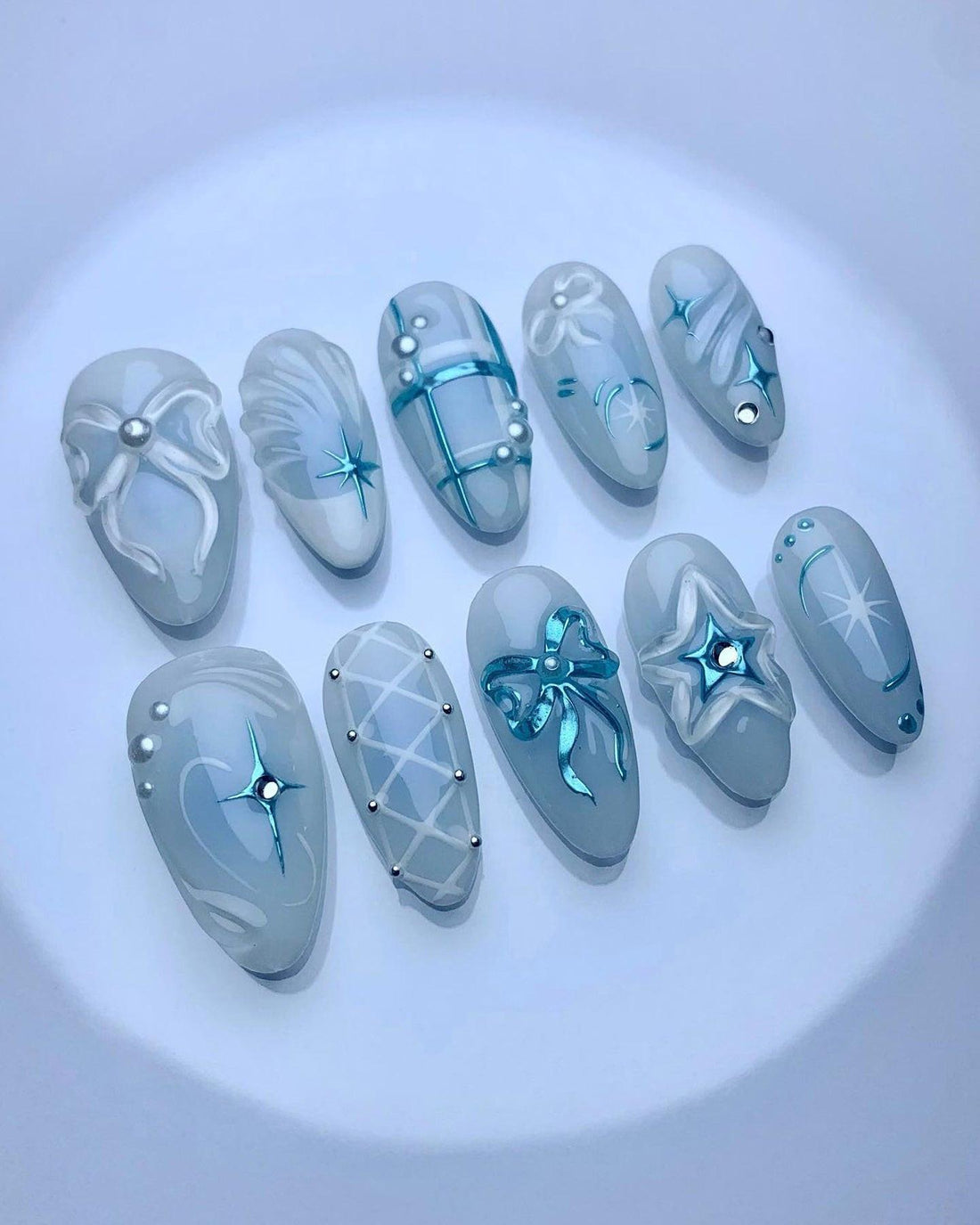 Handmade blue and white press-on nails with 3D bows, pearls, and star designs