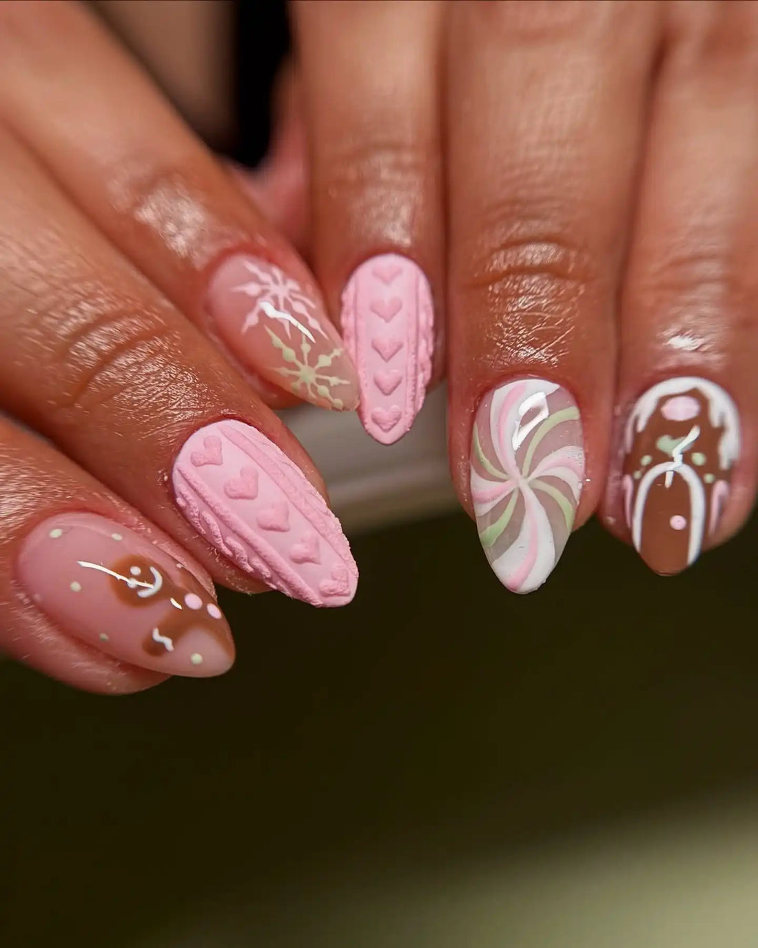 Hand with custom press-on nails in pink and brown, featuring 3D heart and swirl designs.