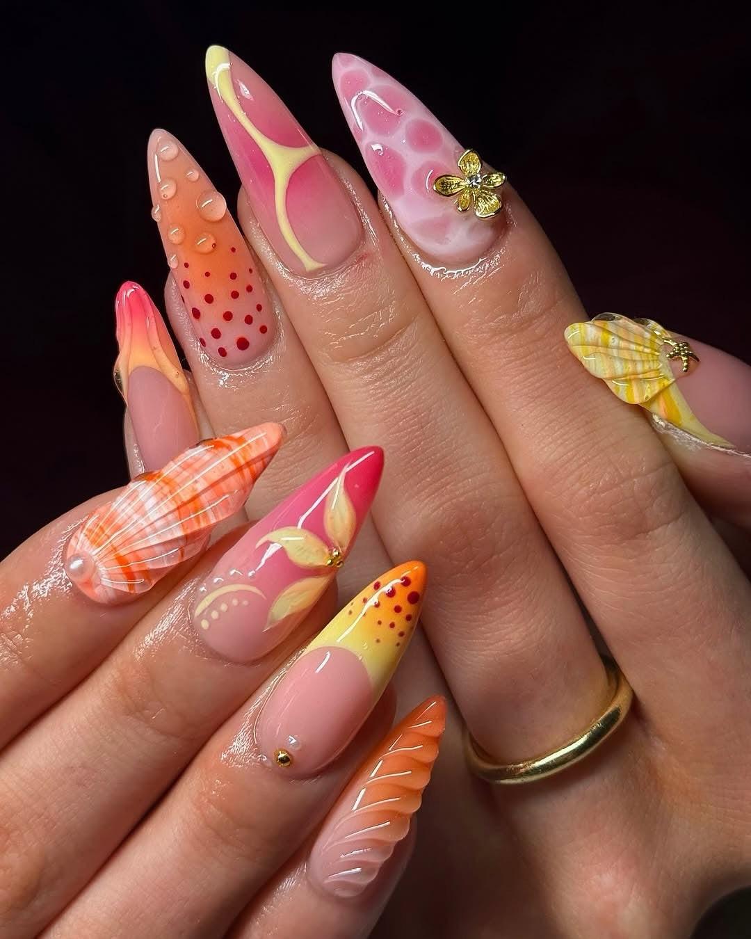 Hand with long, colorful handmade press-on nails featuring floral, ombre, and 3D nail art.