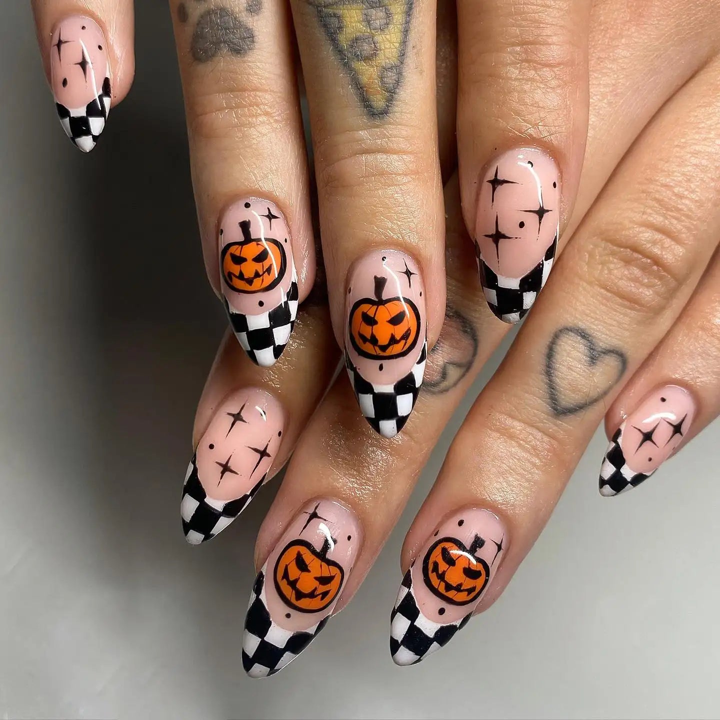 Halloween press-on nails with jack-o'-lantern art and black and white checkered tips.