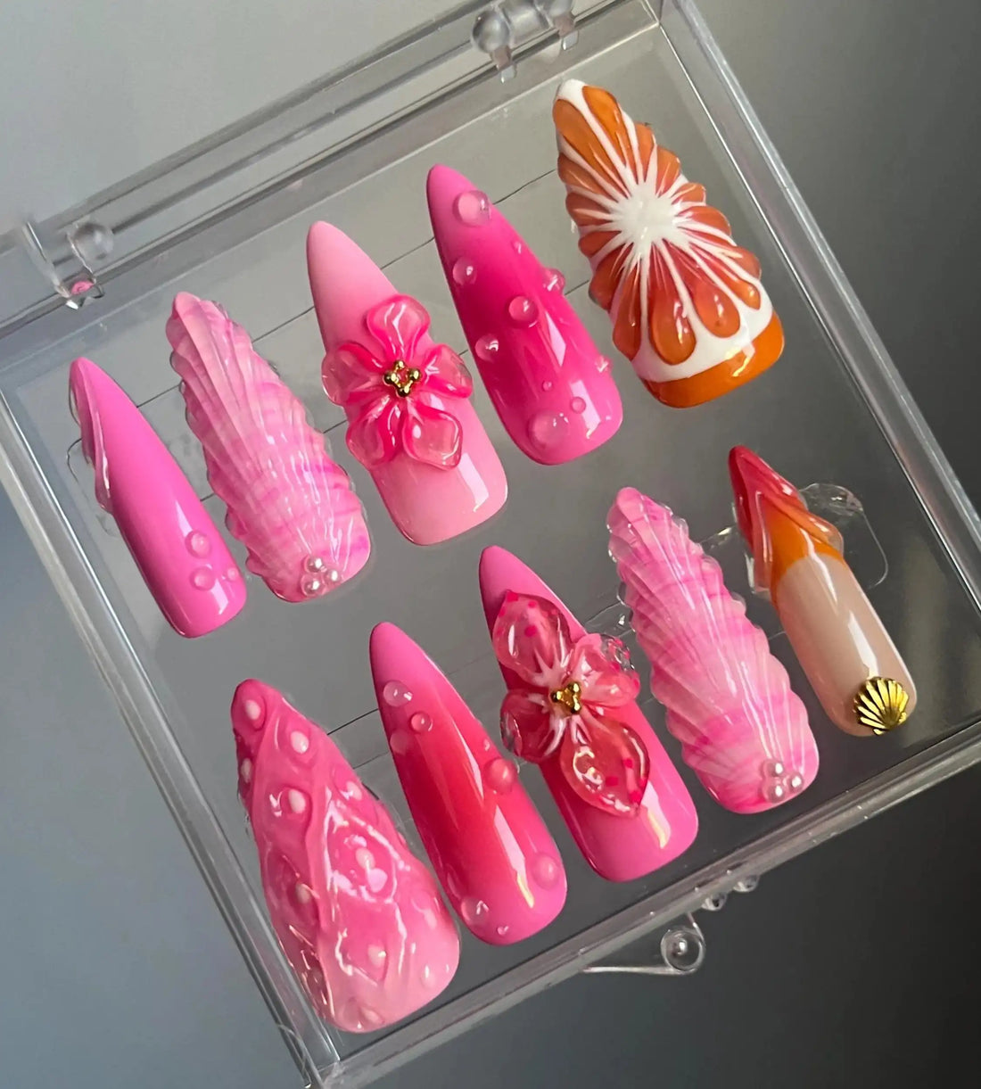 Handmade press-on nails in pink and orange with floral and leaf designs, 3D accents
