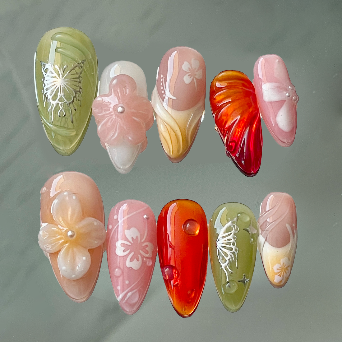Handmade press-on nails with 3D floral designs, butterfly art, and glossy gradient colors