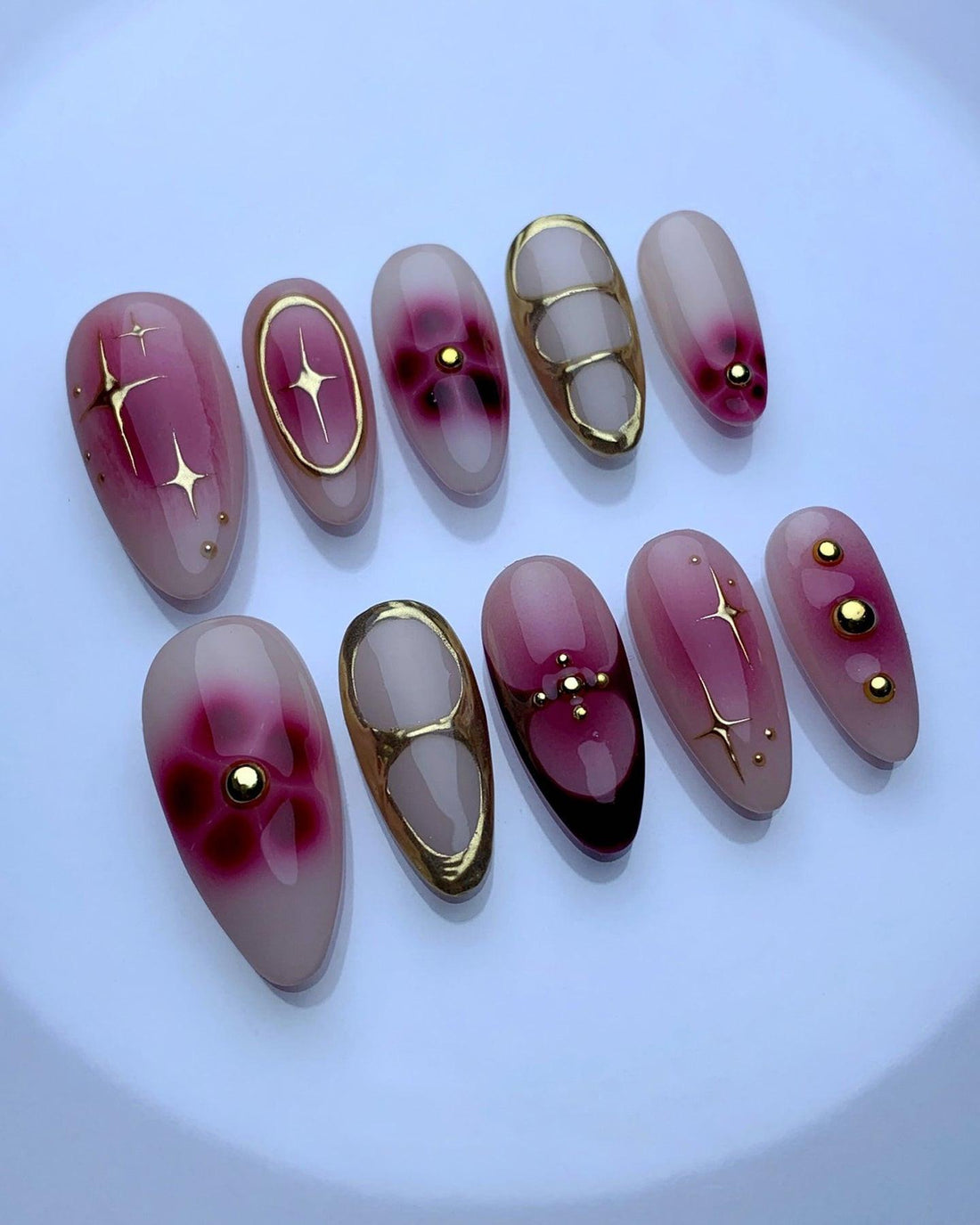 Handmade press-on nails with pink gradient, gold accents, and star designs