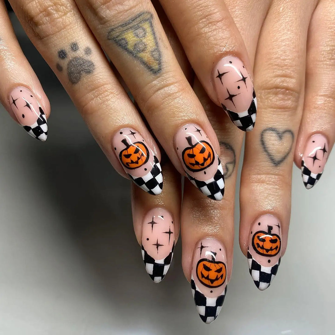 Halloween press-on nails with jack-o'-lantern art and black and white checkered tips.