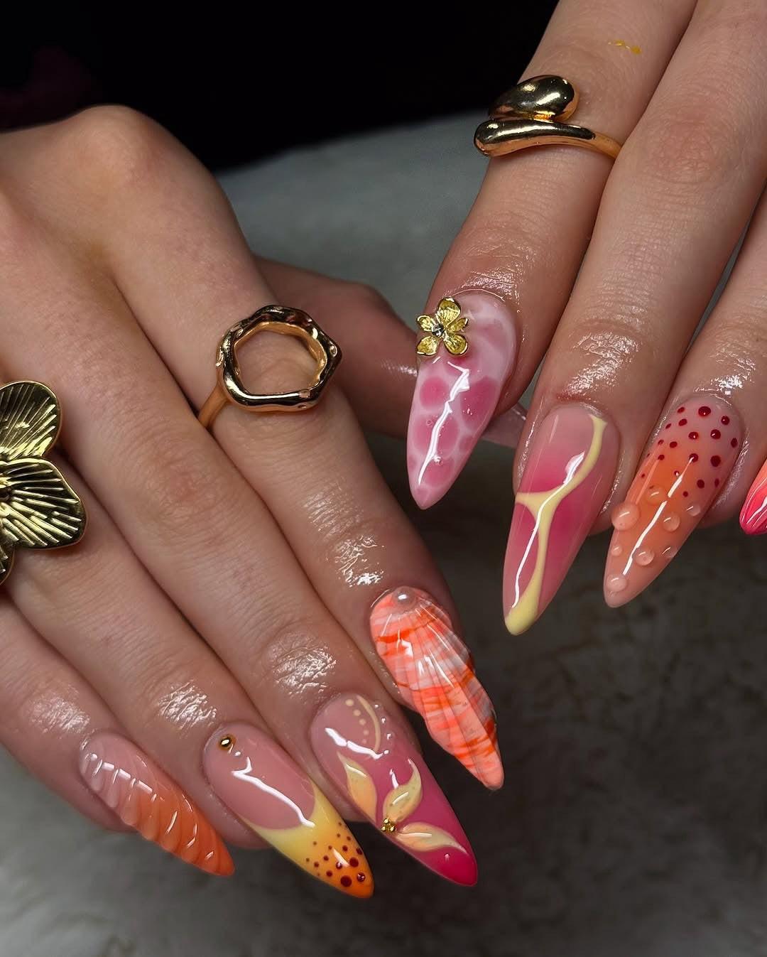 Hand with long, colorful handmade press-on nails featuring floral, ombre, and 3D nail art.