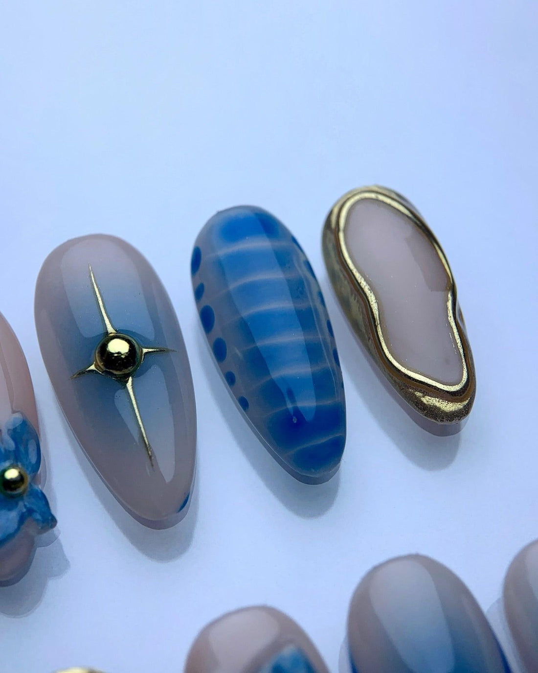 Handmade blue press-on nails with gold accents and floral 3D designs
