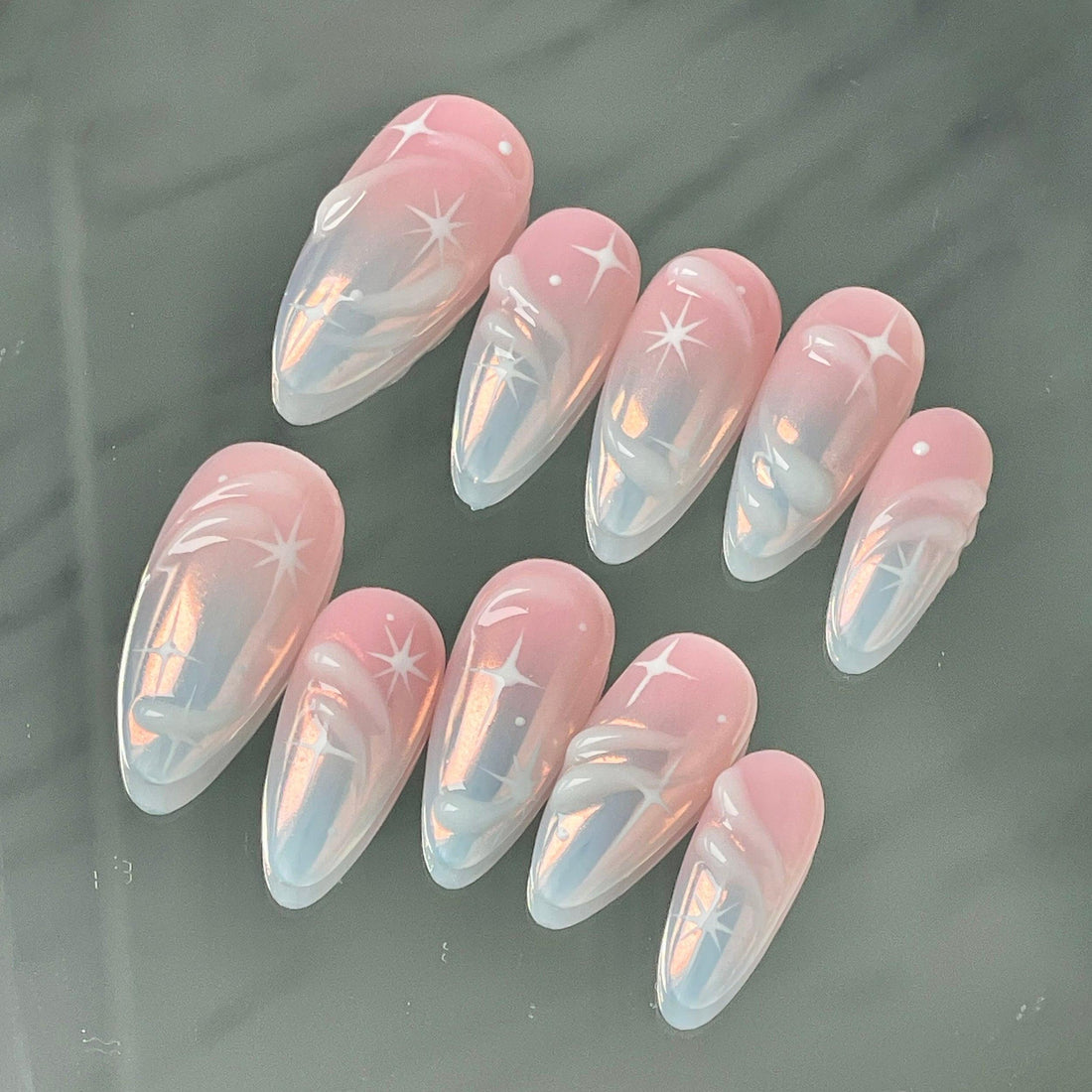 Handmade pink ombre press-on nails with white star and swirl designs, glossy finish