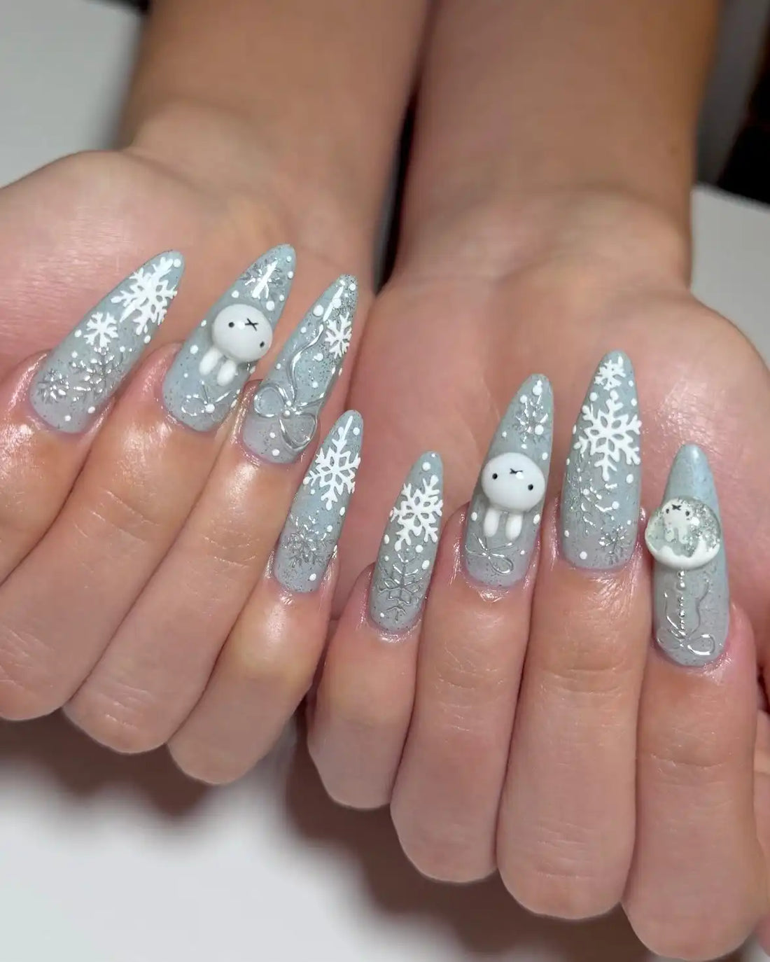 Handmade press-on nails with bunny, snowflake, and glitter winter Christmas designs.