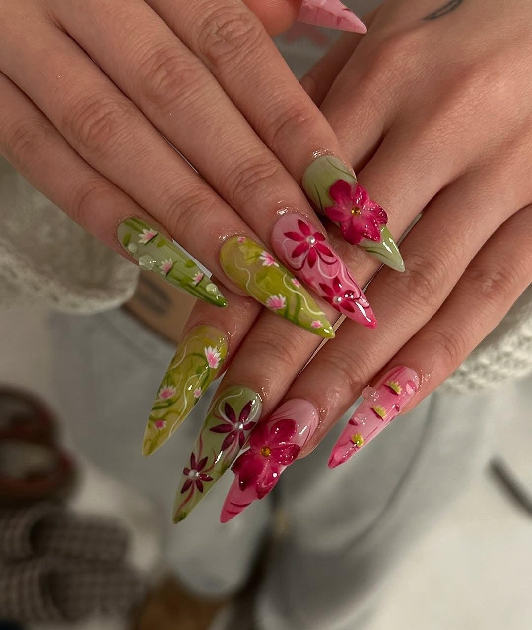 Long press-on nails with green and pink floral designs and 3D flower accents