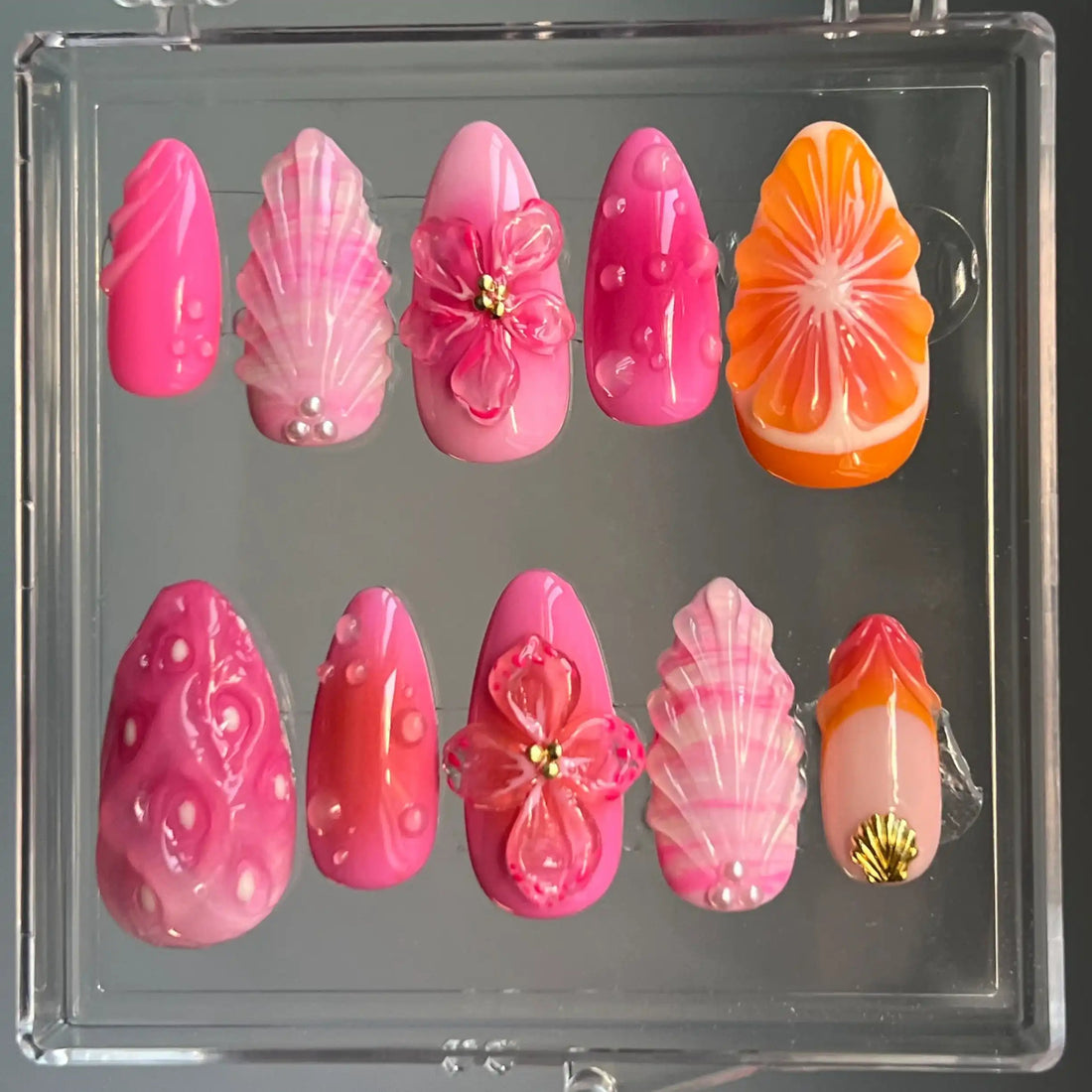 Handmade press-on nails in pink and orange with floral and leaf designs, 3D accents