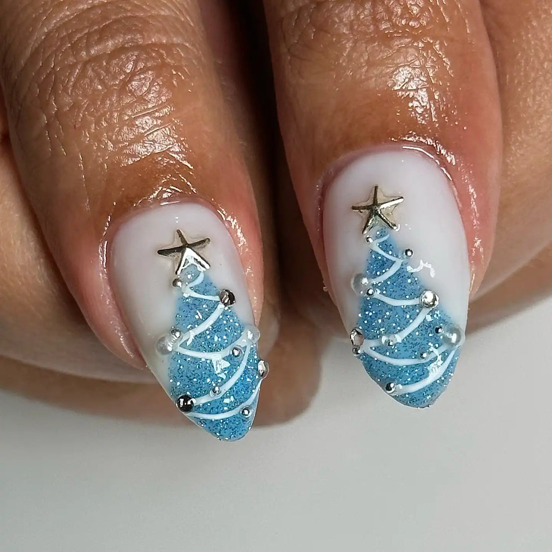 Blue and white winter holiday press-on nails with snowflakes, bows, and glitter accents