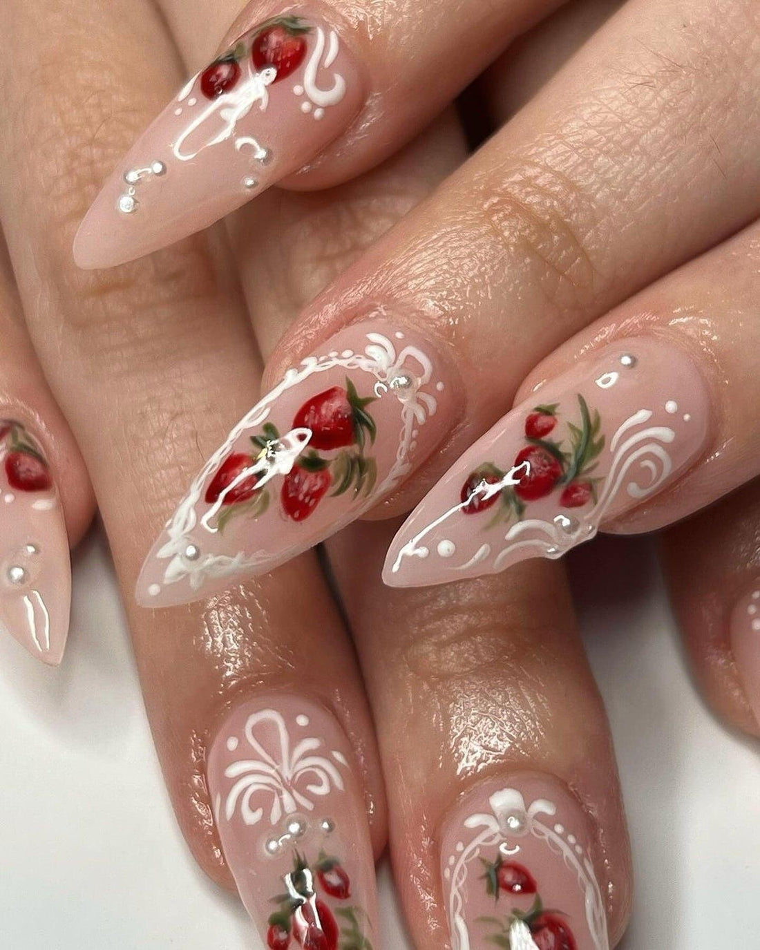 Long almond press-on nails with hand-painted red floral and white swirl designs