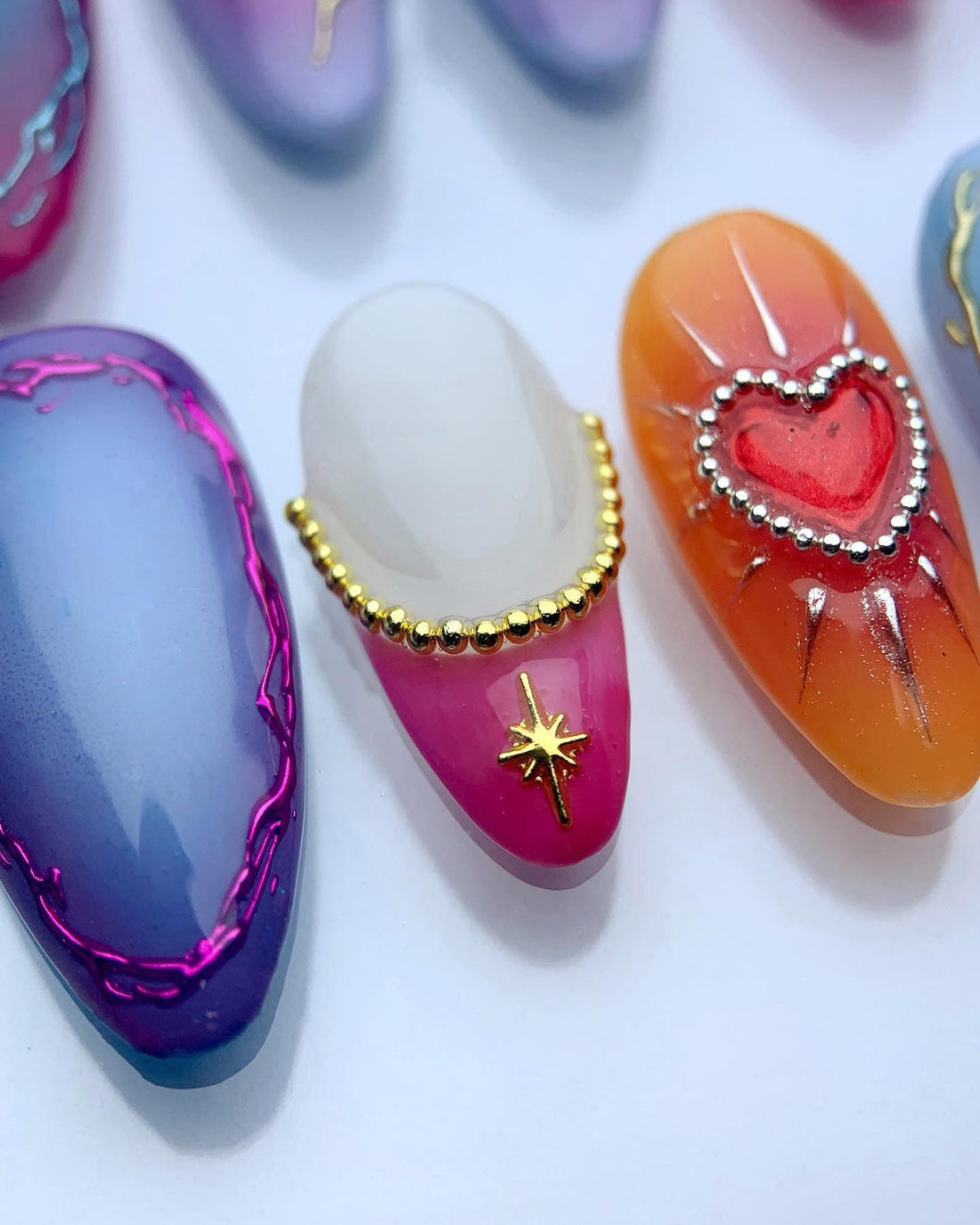 Handmade press-on nails with colorful designs, including butterfly, heart, and star art