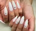 Hand with long white press-on nails featuring cute ghost and mummy nail art designs