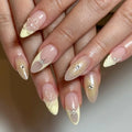 Hand with light yellow French tip press-on nails, 3D floral designs and pearl accents