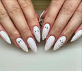 Hand with white stiletto press-on nails featuring cute ghost and mummy nail art designs.