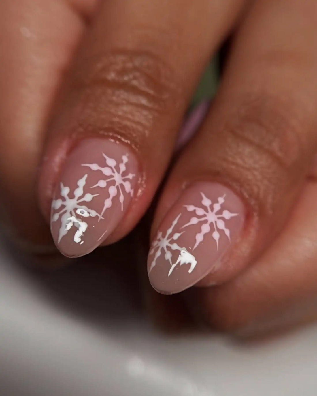 Hand with custom press-on nails in pink and brown, featuring 3D heart and swirl designs.
