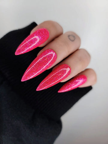 Hand wearing long stiletto hot pink glitter press-on nails, close-up view