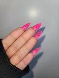 Hand with long stiletto-shaped pink glitter press-on nails, close-up