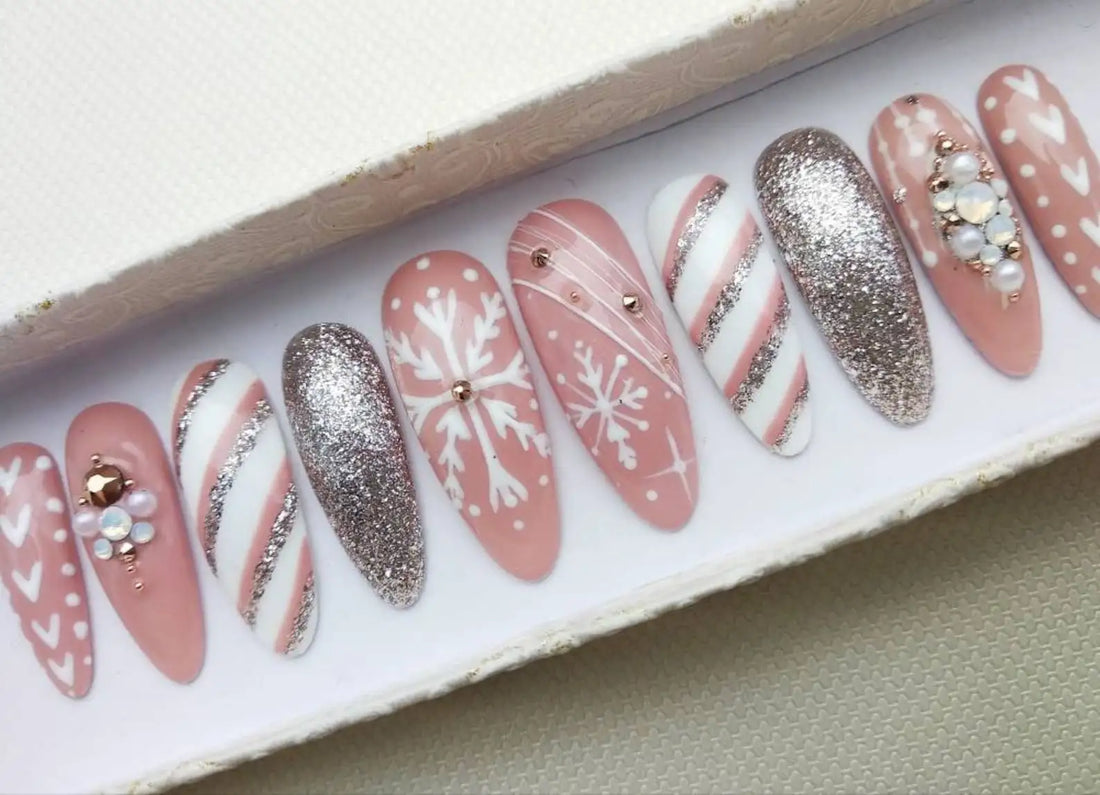 Pink press-on nails with white snowflake, glitter, candy cane, and pearl designs for Christmas.