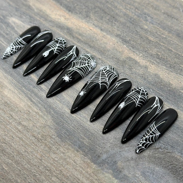 Black stiletto press-on nails with white spider web and spider Halloween nail art
