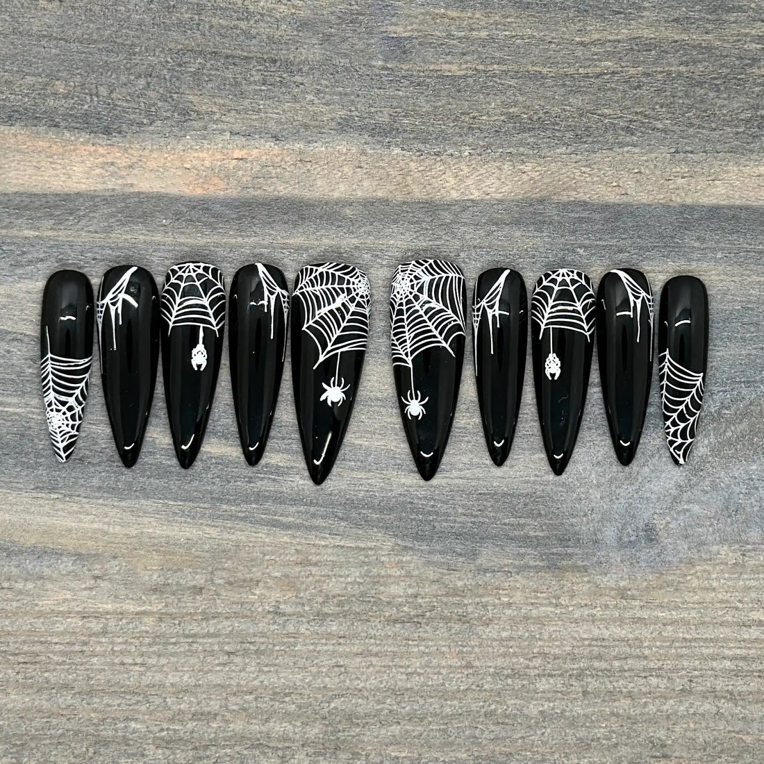 Black stiletto press-on nails with white spider web and spider Halloween nail art