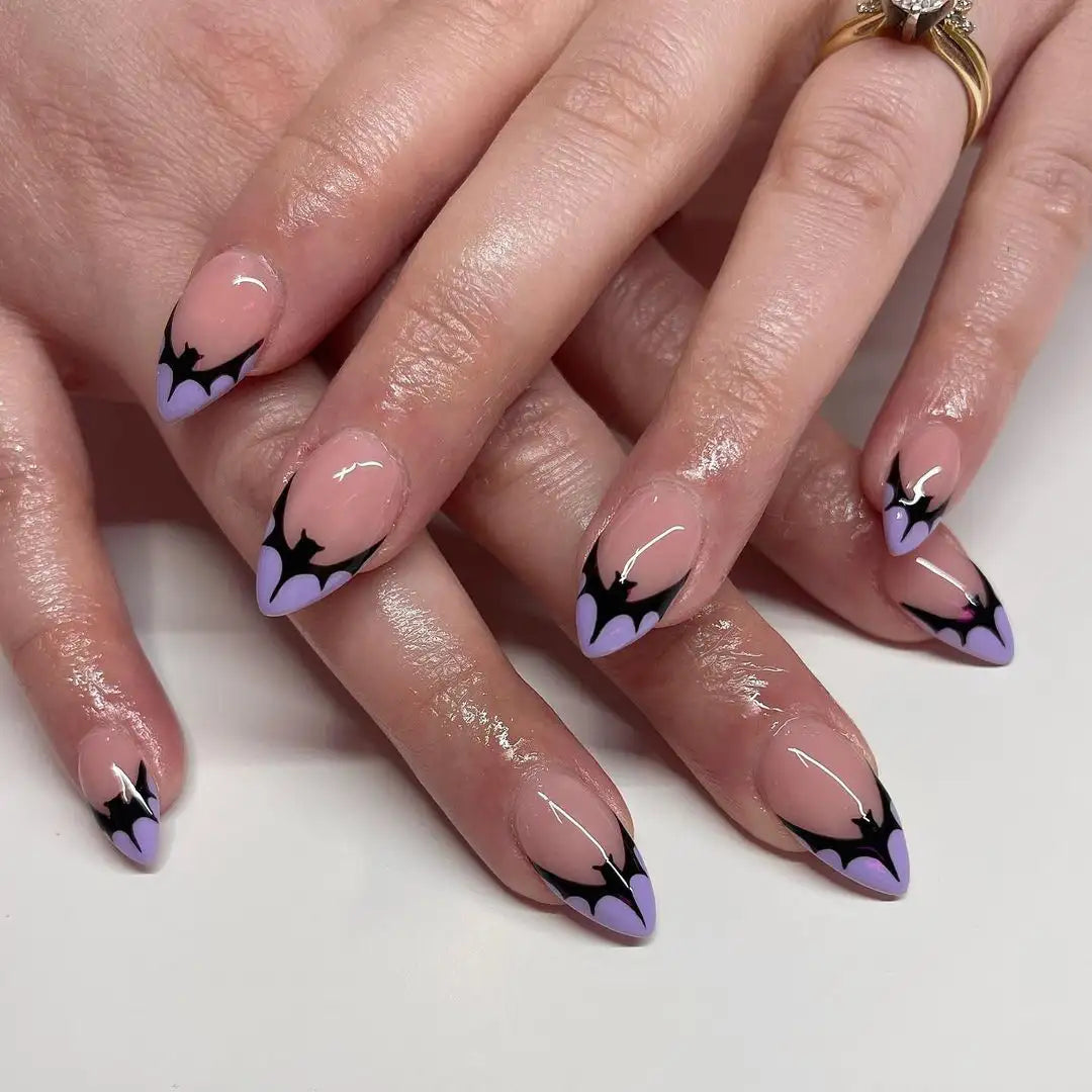 Hand with purple and black bat-themed Halloween press-on nails, pointed shape, handmade design