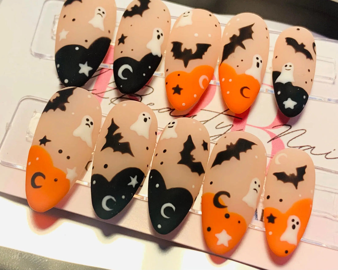 Halloween press-on nails with ghost, bat, moon, and star designs in orange and black