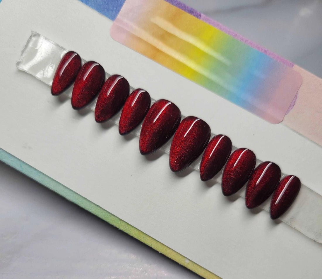 Set of glossy red cat eye coffin-shaped press-on nails displayed on white background