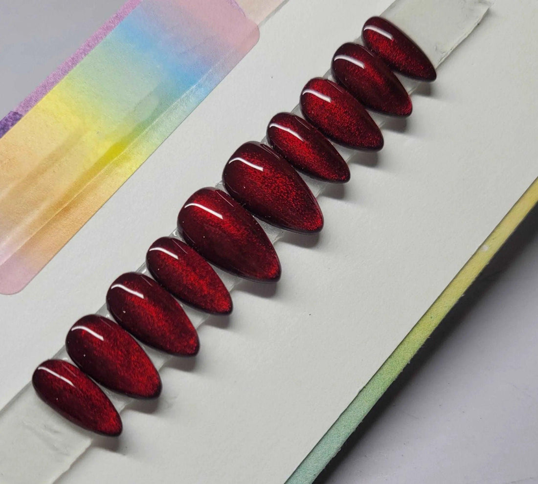 Set of glossy red cat eye coffin-shaped press-on nails displayed on white background