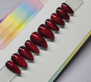 Set of glossy red cat eye coffin-shaped press-on nails displayed on white background
