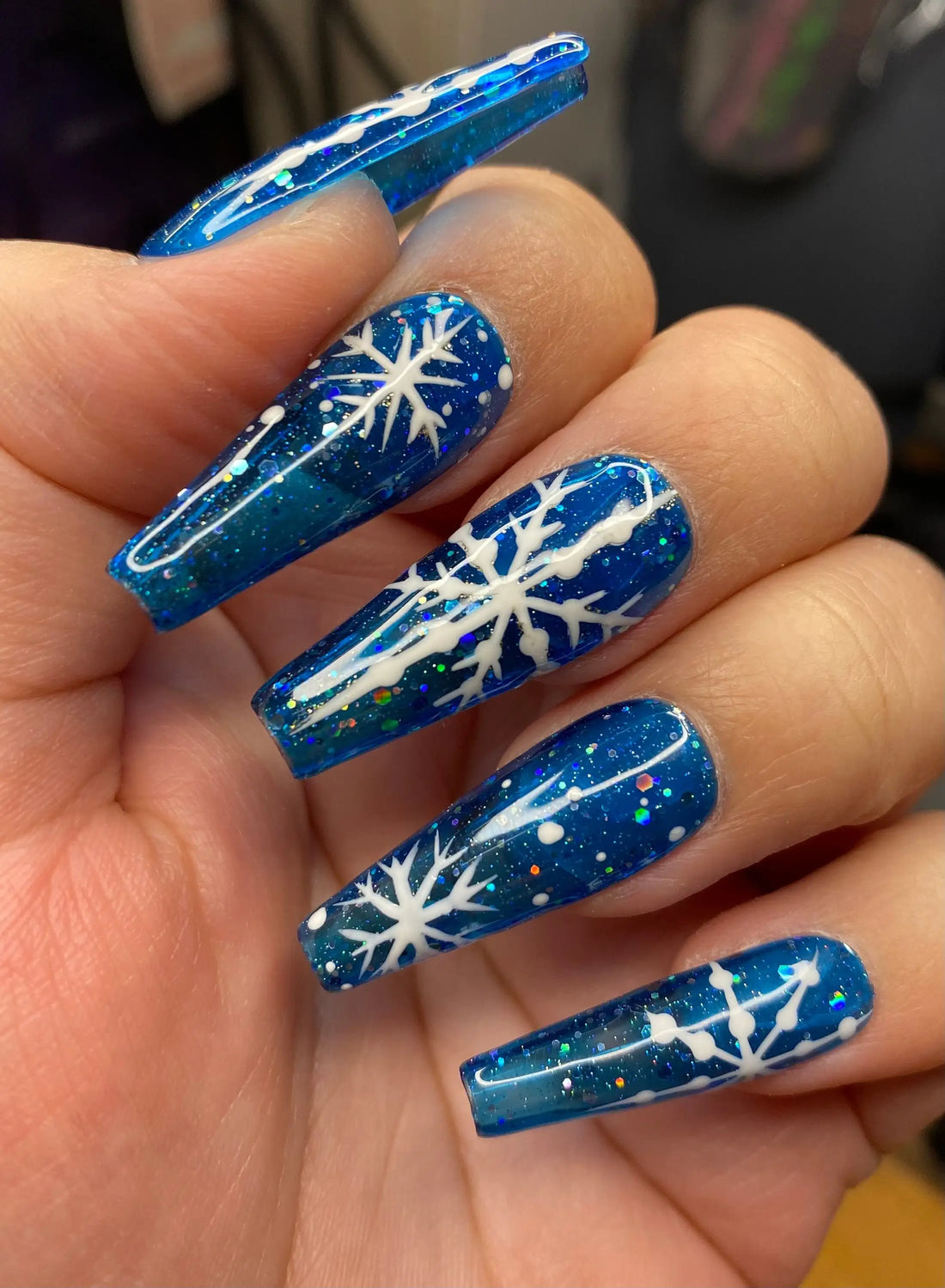 Blue glitter press-on nails with white snowflake Christmas design, long coffin shape