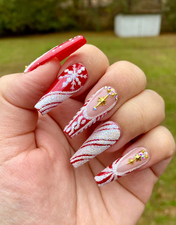 Red Christmas press-on nails with glitter, snowflakes, stars, and candy cane designs