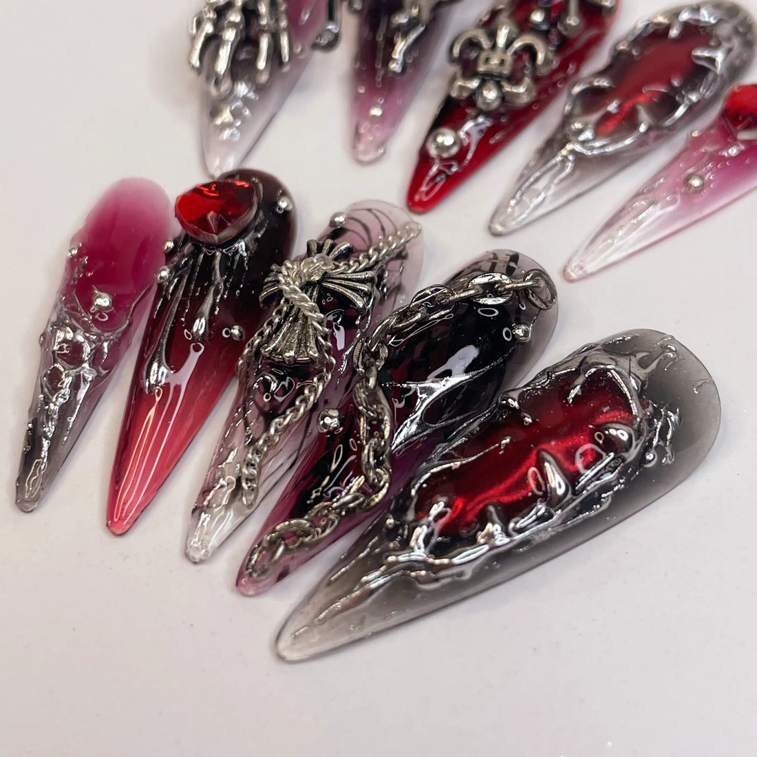 Long red and black press-on nails with silver gothic charms and 3D accents