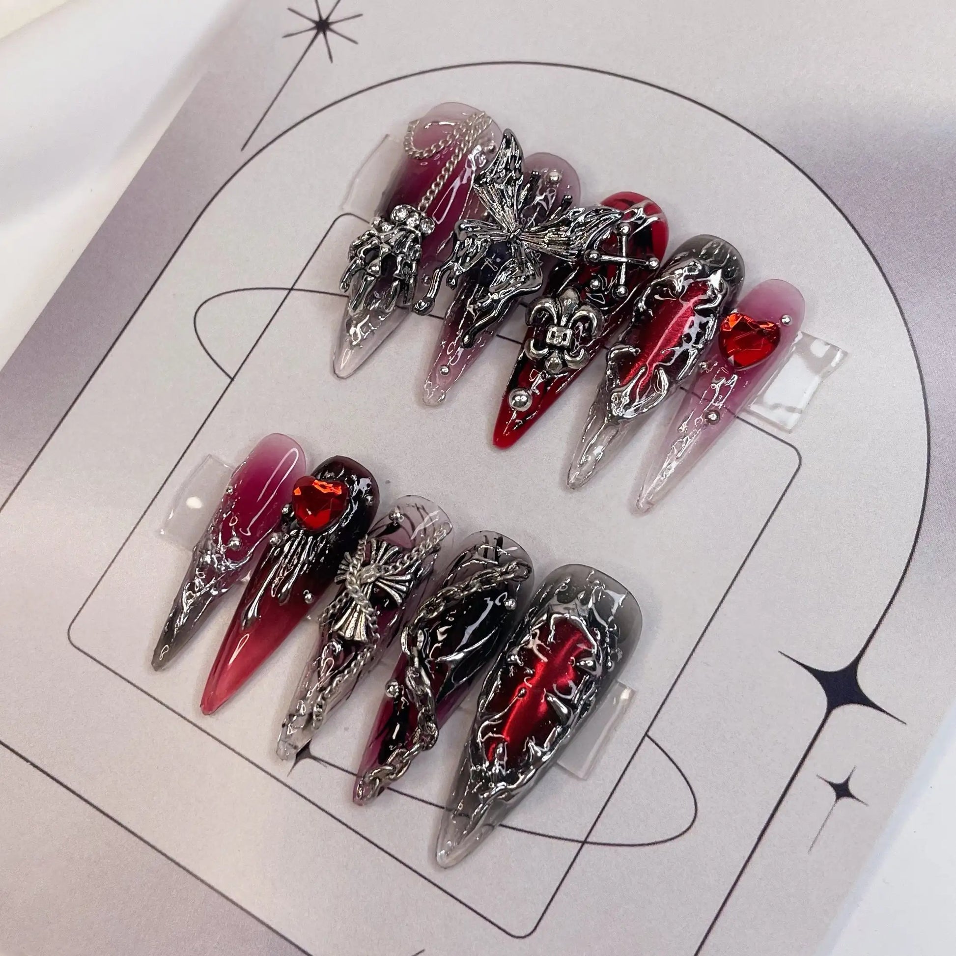 Red and black press-on nails with gothic silver cross charms and heart jewels