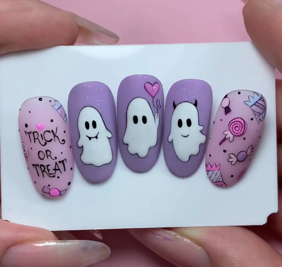 Cute Halloween press-on nails with pastel ghosts, trick or treat text, and candy designs.