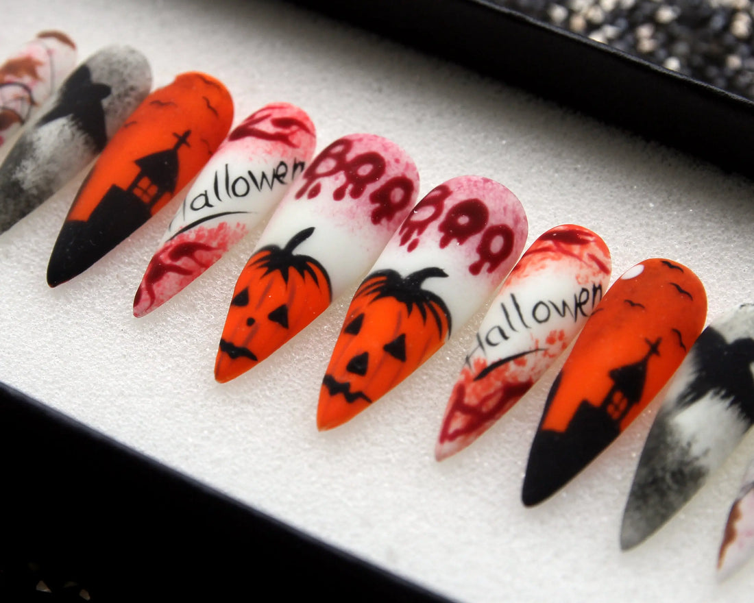 Halloween press-on nails with pumpkin, skull, and haunted house designs in orange, black, and red.