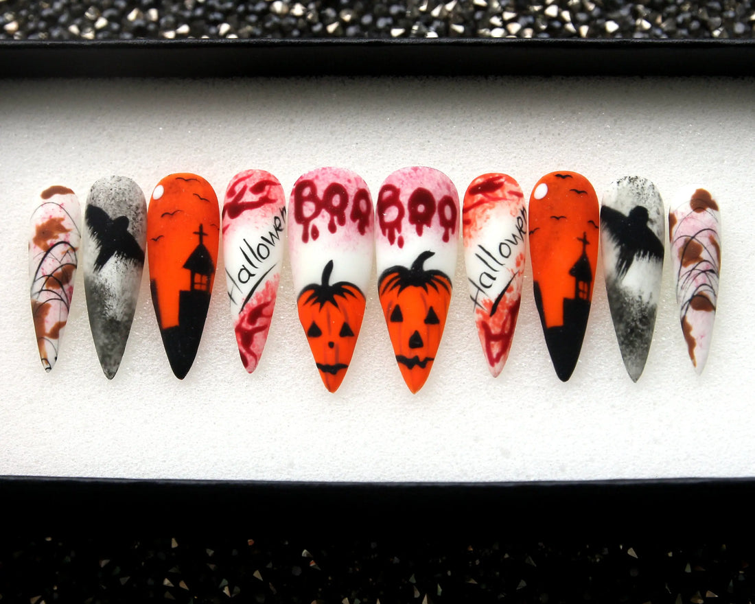 Halloween press-on nails with pumpkin, skull, and haunted house designs in orange, black, and red.