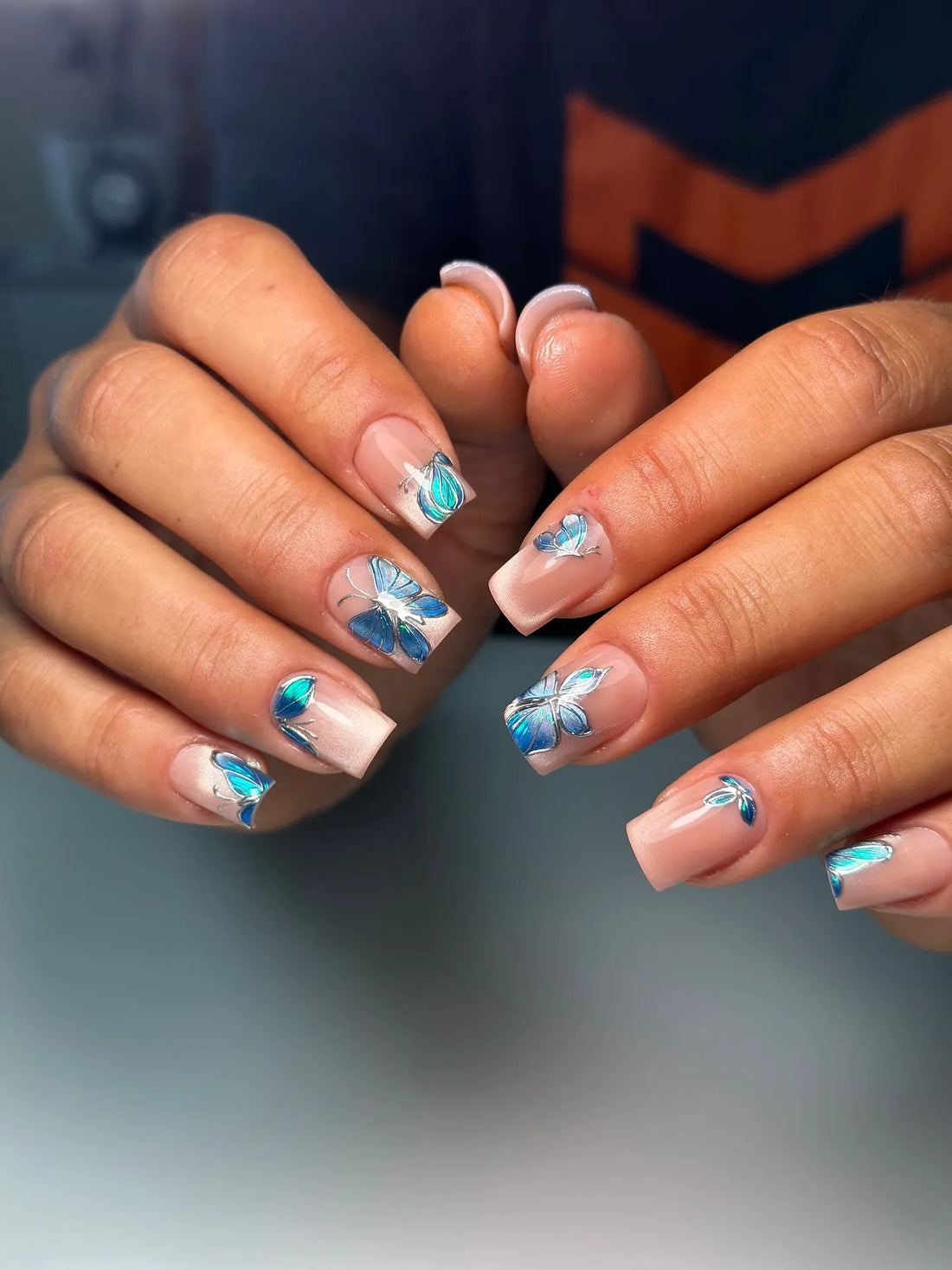 Handmade nude base press-on nails with 3D blue chrome butterfly details