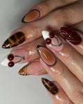Handmade 3D press-on nails with cherry, chocolate brown, tortoise shell, and animal print designs