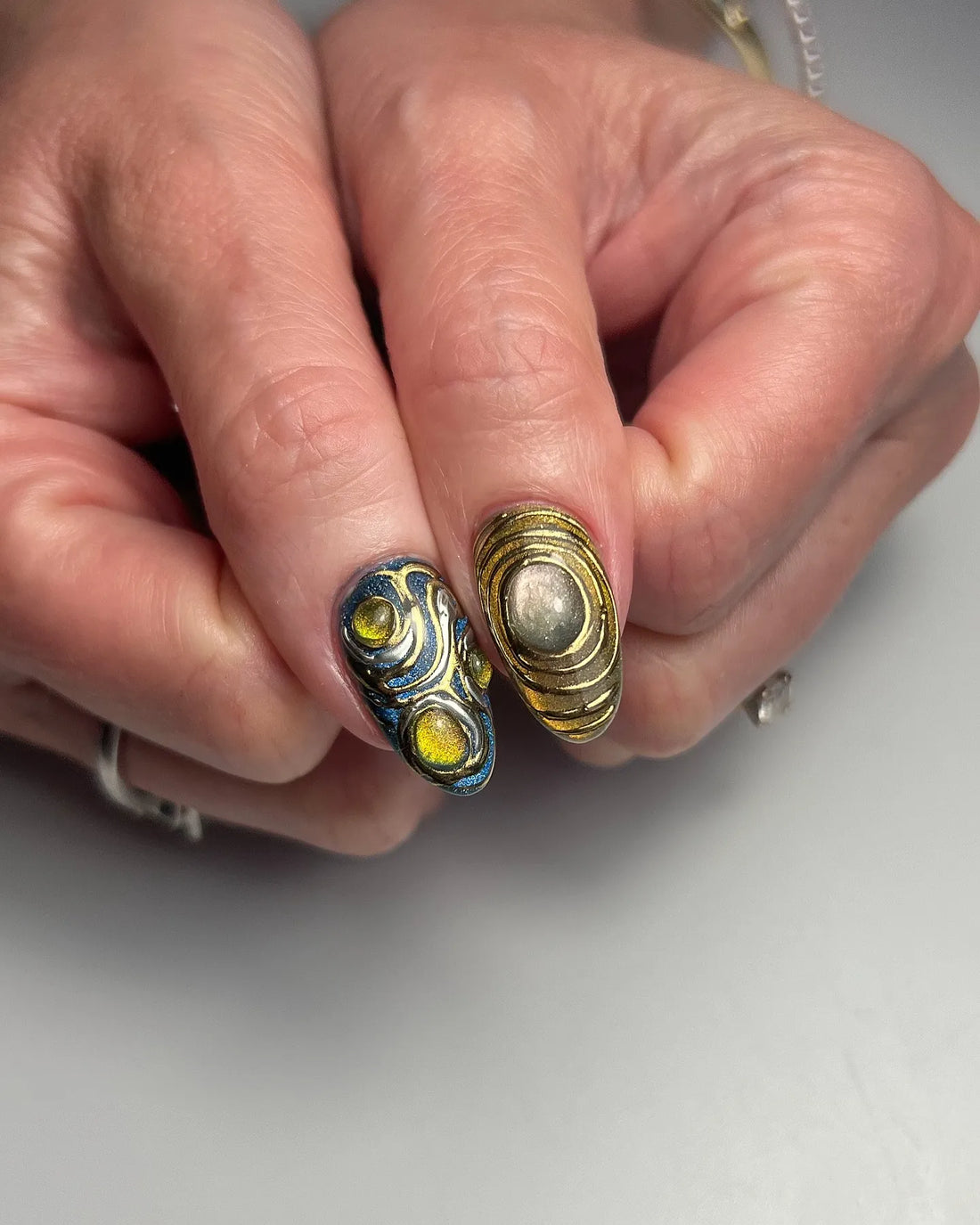 Handmade 3D metallic press-on nails with gemstone accents in chrome, gold, and colorful designs.