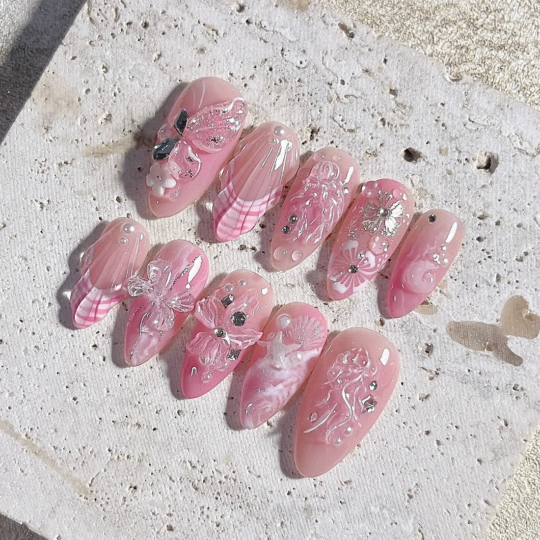 Handmade pink press-on nails with 3D butterfly, seashell, floral, and pearl gem accents
