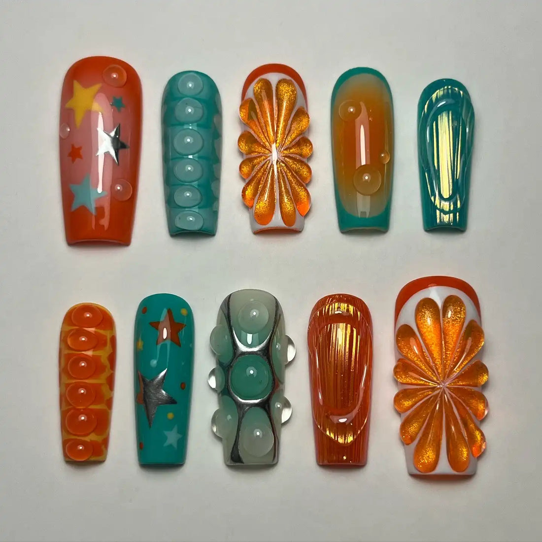 Handmade abstract press-on nails with citrus, star, teal, orange, and water drop designs