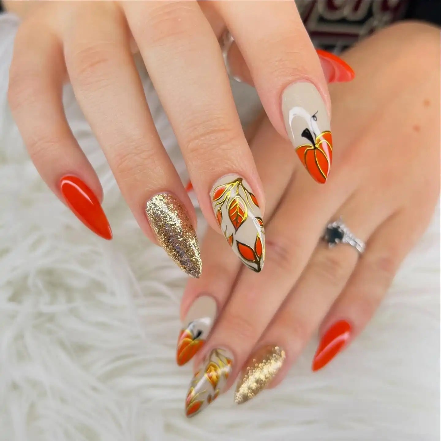 Handmade autumn press-on nails with pumpkin, gold glitter, and fall leaves designs.