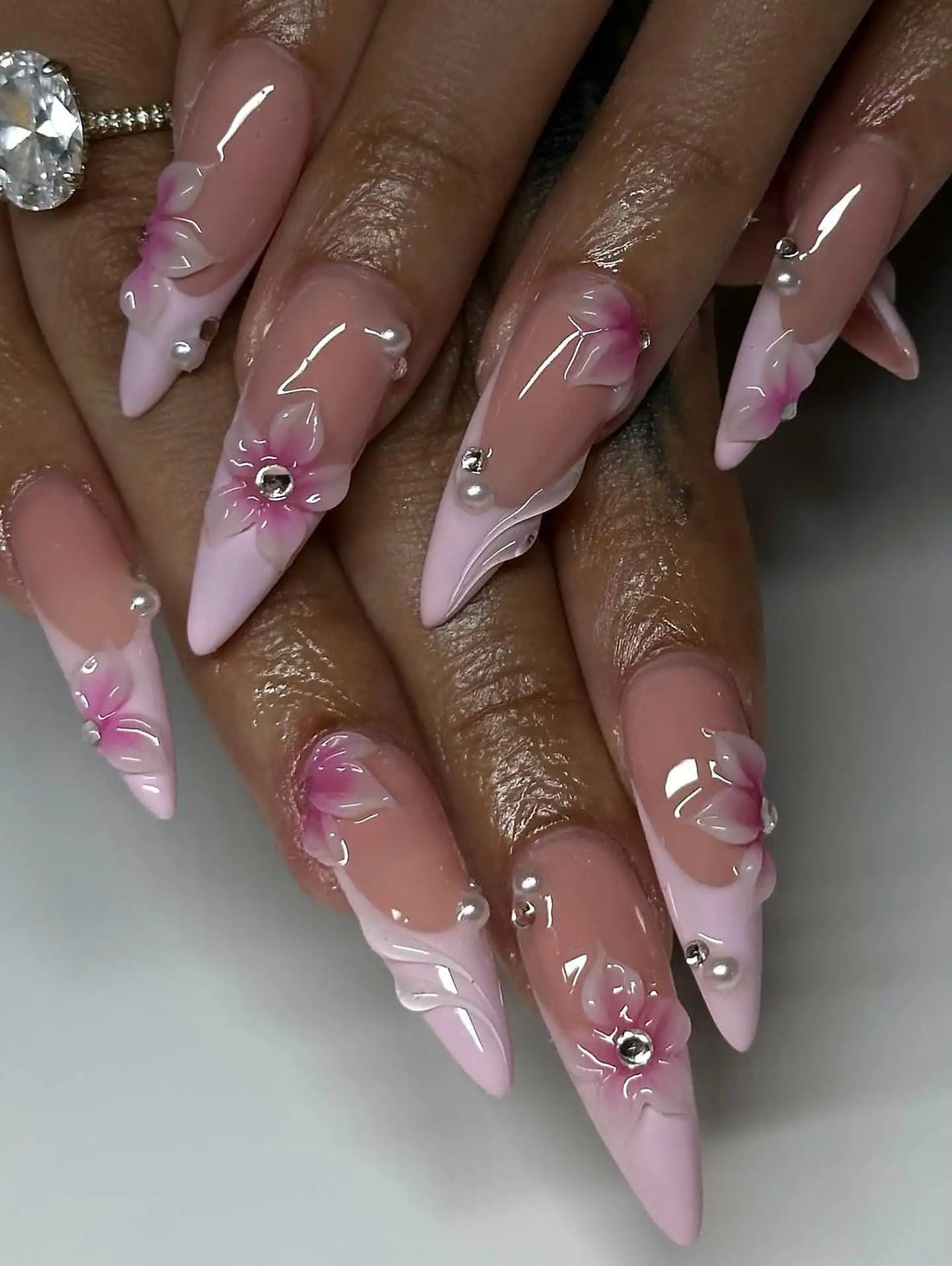 Handmade pink press-on nails with French tips, 3D floral accents, pearls, and gemstones.