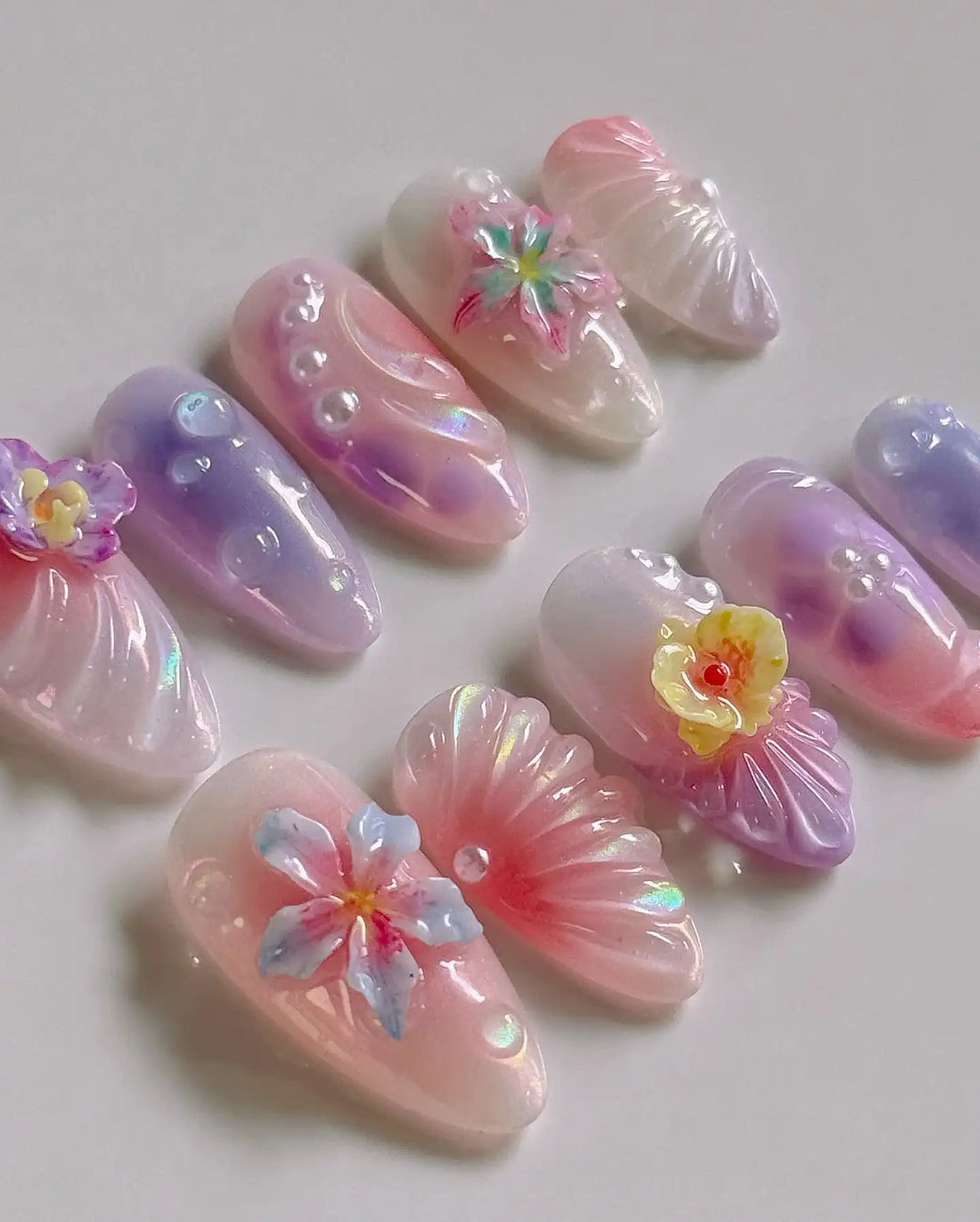 Handmade pink ombre press-on nails with 3D floral designs and pearl accents