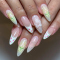 Hand with long almond-shaped press-on nails featuring pink strawberry French tips, bows, floral art, and 3D accents.